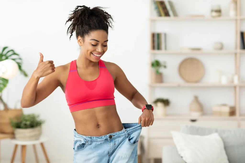happy woman shows weight loss in loose jeans utc